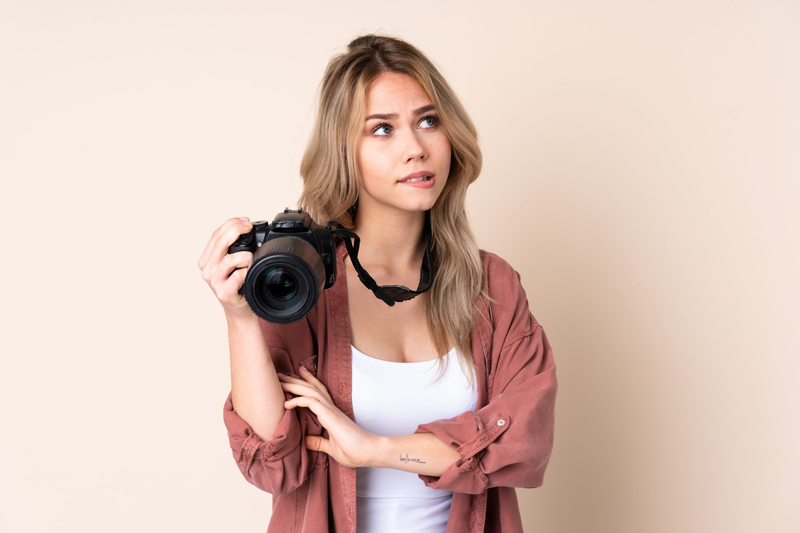Junge Frau Kamera ueberlegt scaled - Fotografie-Recht: Was darf ich alles fotografieren?